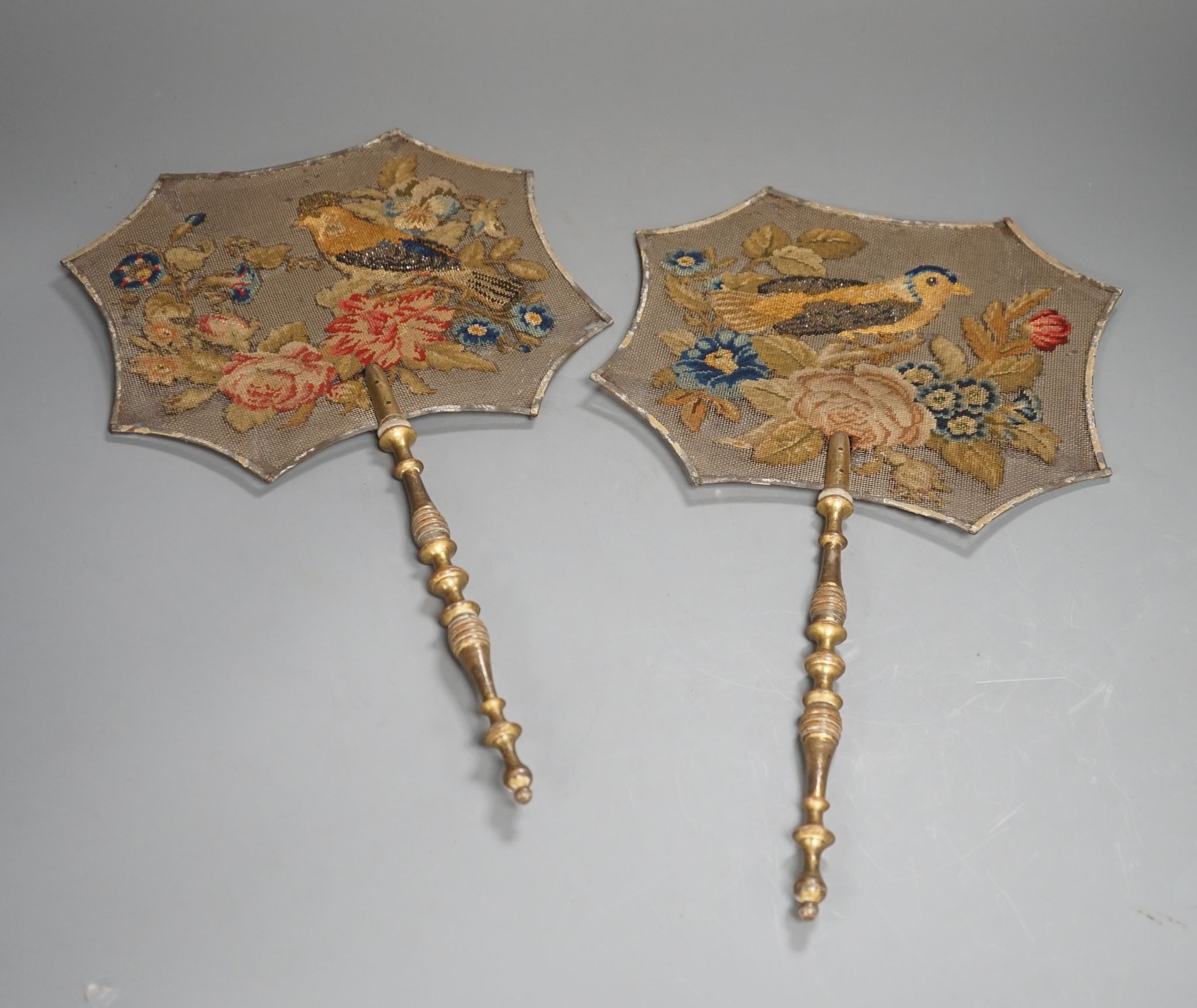 A pair of early Victorian petite point and cut steel hand screens, 39 cms high.